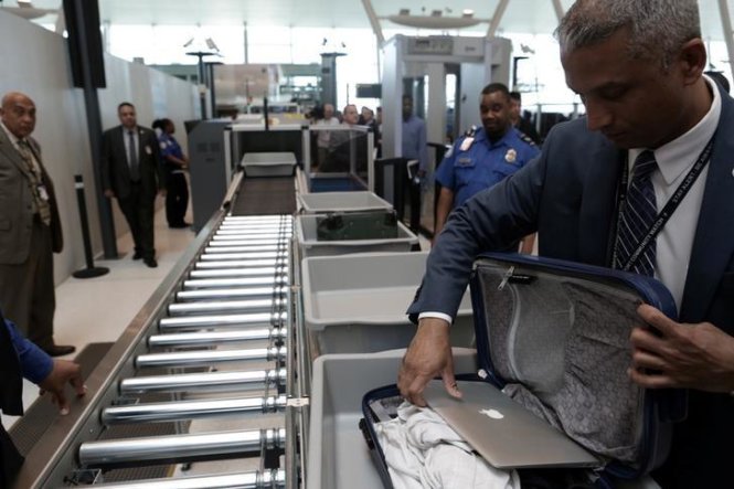Một nhân viên kiểm tra an ninh lấy chiếc laptop ra khỏi hành lý của một khách tại sân bay JSK ở New York City, Mỹ - Ảnh: Reuters