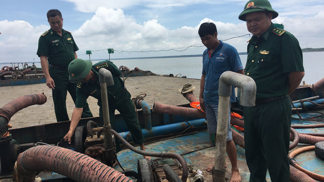 Các cán bộ đồn Biên phòng Long Hòa đang kiểm tra xà lan mang biển số Sài Gòn chở đầy cát - Ảnh: MY LĂNG