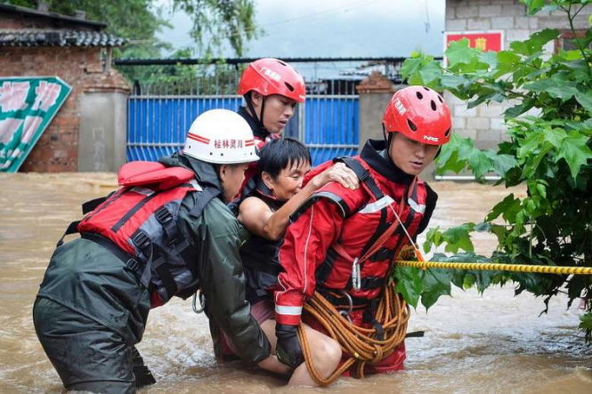 Nhân viên cứu hộ đang giúp một bà cụ vượt qua con đường ngập nước ở Quế Lâm, tỉnh Quảng Tây - Ảnh: AFP