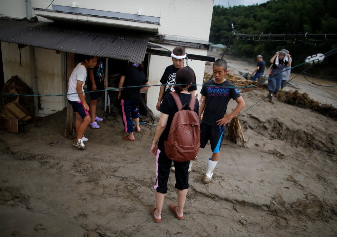 Một gia đình ở thành phố Asakura thất thần trước căn nhà của họ đang ngập trong bùn vào sáng 8-7 - Ảnh: Reuters
