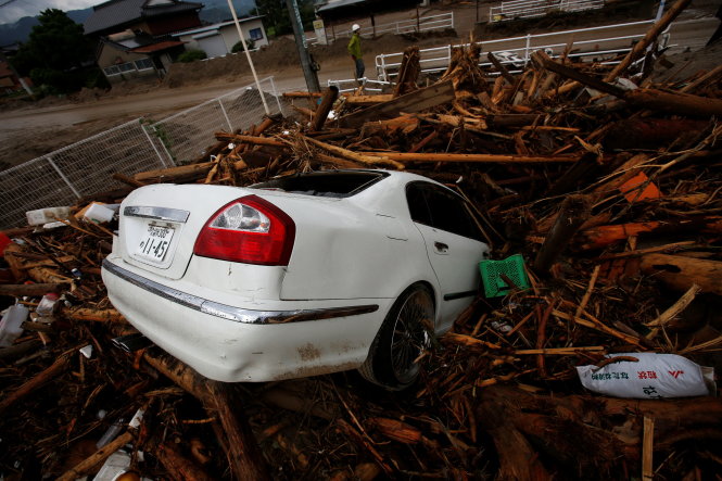 Cây cối theo dòng lũ nhấn chìm cả chiếc xe hơi của một hộ dân - Ảnh: Reuters