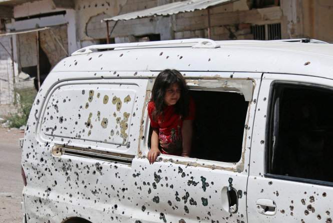 Một bé gái Syria nhoài người ra khỏi một chiếc ôtô chi chít vết đạn ở thành phố Daraa, Syria ngày 9-7, vài tiếng sau khi lệnh ngừng bắn có hiệu lực - Ảnh: Reuters