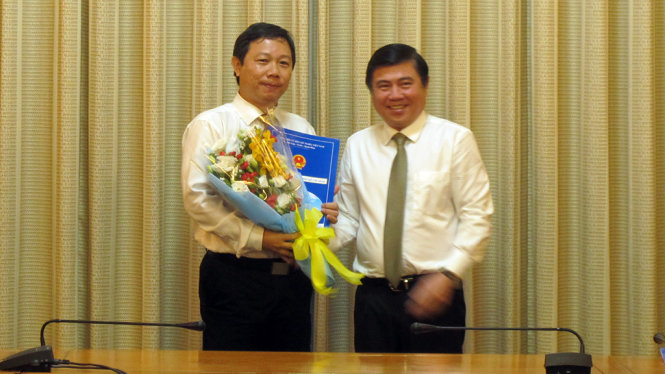 Chủ tịch UBND TP.HCM Nguyễn Thành Phong tặng hoa, trao quyết định cho ông Dương Anh Đức - Ảnh: Nguyễn Đình