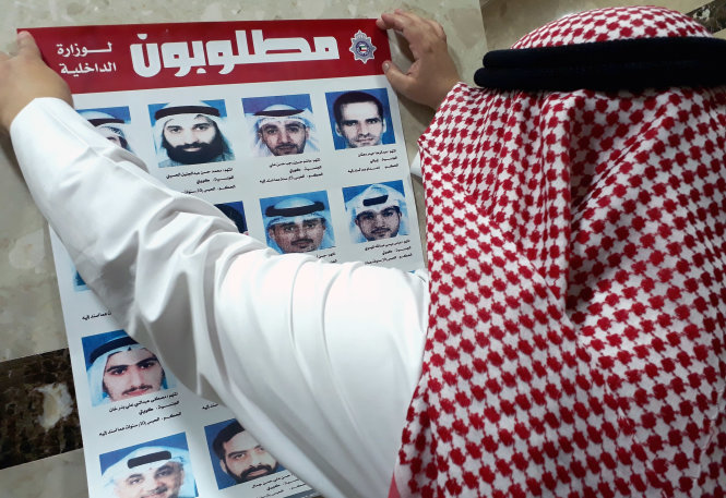 Một quan chức Bộ Nội vụ Kuwait dán bảng thông báo về những phạm nhân đào tẩu hôm 19-7 - Ảnh: AFP