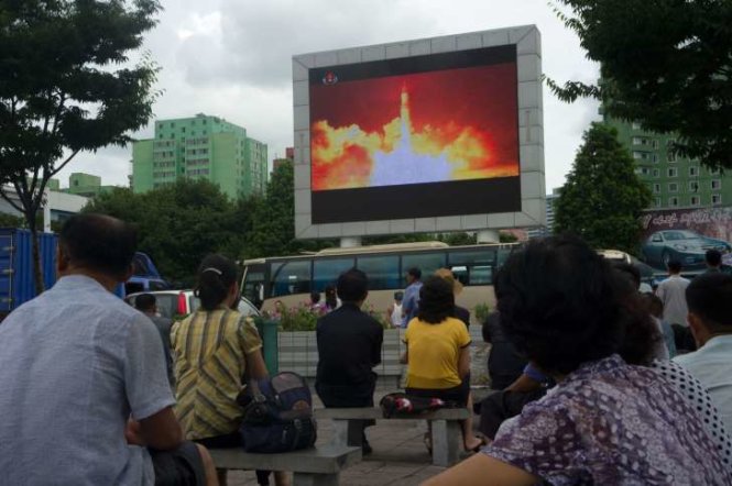 Người dân ngồi xem bản tin về một cuộc phóng thử tên lửa ICBM trên màn hình công cộng ở Bình Nhưỡng ngày 29-7 - Ảnh: AFP