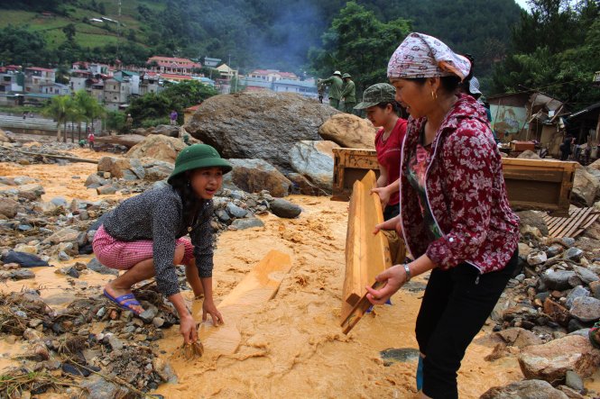 Người dân tổ 8, thị trấn Mù Cang Chải mang đồ đạc dính bùn đất ra dòng nước lũ để cọ rửa - ẢNH: CHÍ TUỆ
