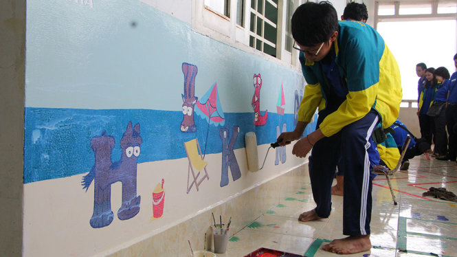 Sinh viên ĐH Kiến trúc đang sơn bảng chữ cái đầy màu sắc cho trường mẫu giáo tại Tây Ninh - Ảnh: THU TRANG