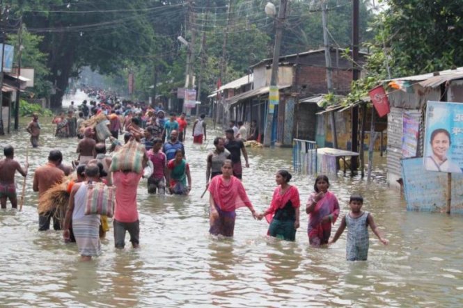 Người dân lội trong nước lũ tại Balurghat ở Tây Bengal, Ấn Độ hôm 17-8 - Ảnh: AFP