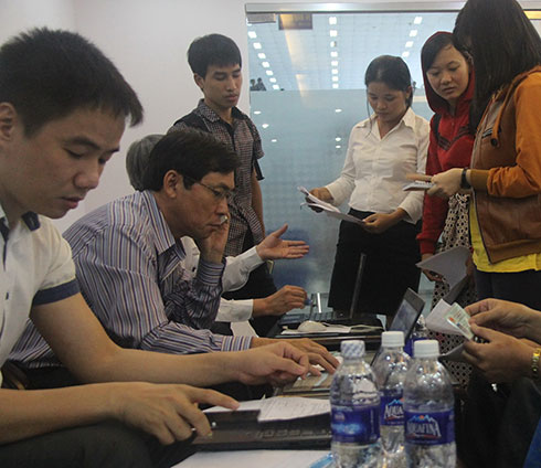 Ông Nguyễn Văn Thành - trưởng ga Sài Gòn (thứ hai từ trái sang) - trực tiếp giải quyết các thắc mắc của hành khách gặp sự cố khi đặt chỗ qua mạng ngày 4-12 - Ảnh: Q.Khải