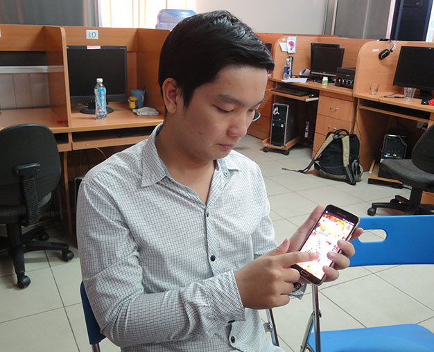 ThS Trần Minh Trường dùng điện thoại có cài phần mềm hỗ trợ đọc tiếng Việt - Ảnh: Mỹ Dung