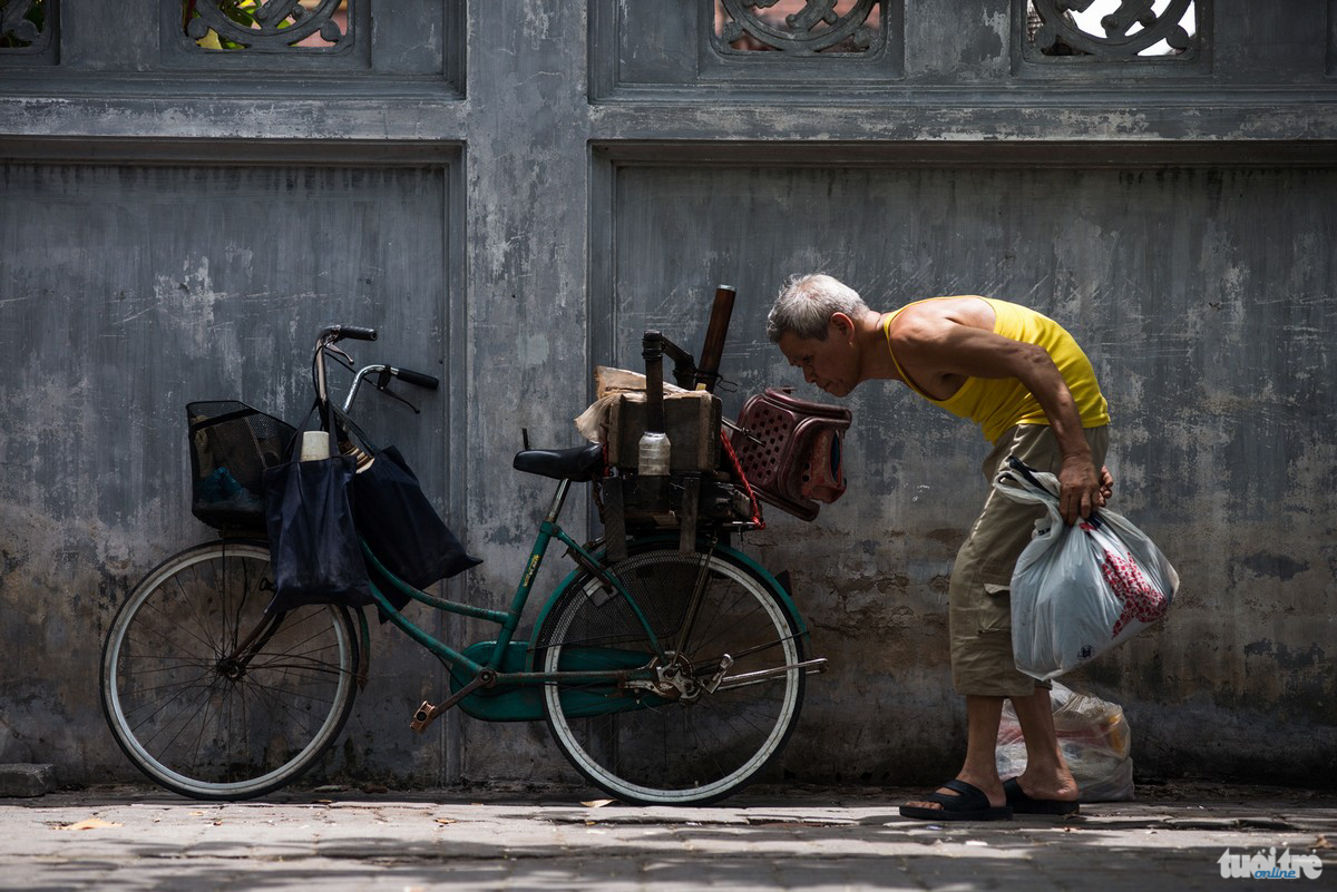 Ông Doãn, 72 tuổi cùng chiếc thùng đồ bán trà và chiếc xe đạp cũ. Ông bán trà cạnh nhà máy dệt Nam Định hơn 27 năm nay - Ảnh: NAM TRẦN