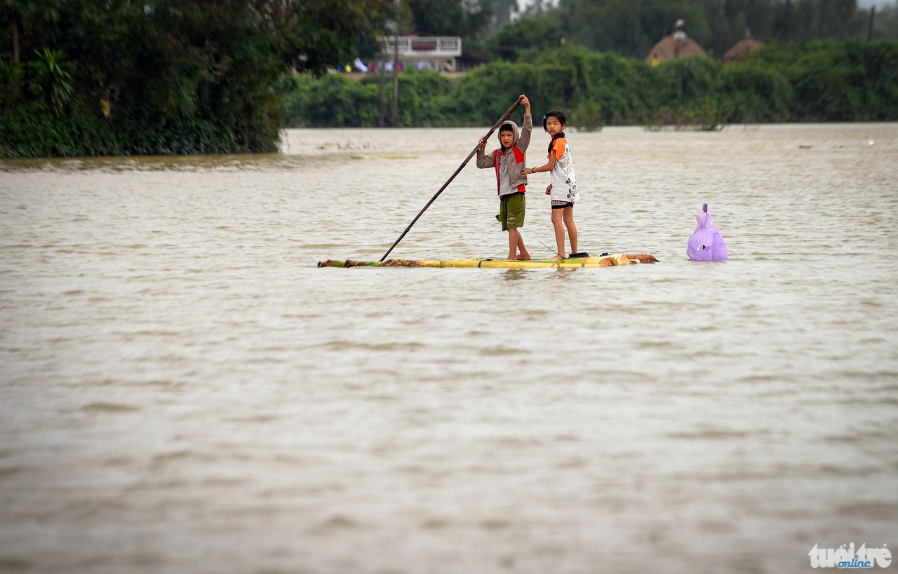Trẻ em Thôn Diêu Trì, Thị trấn Diêu Trì, huyện Tuy Phước, tỉnh Bình Địn đi lại bằng bè chuối trong dòng nước lũ - Ảnh: HỮU KHOA