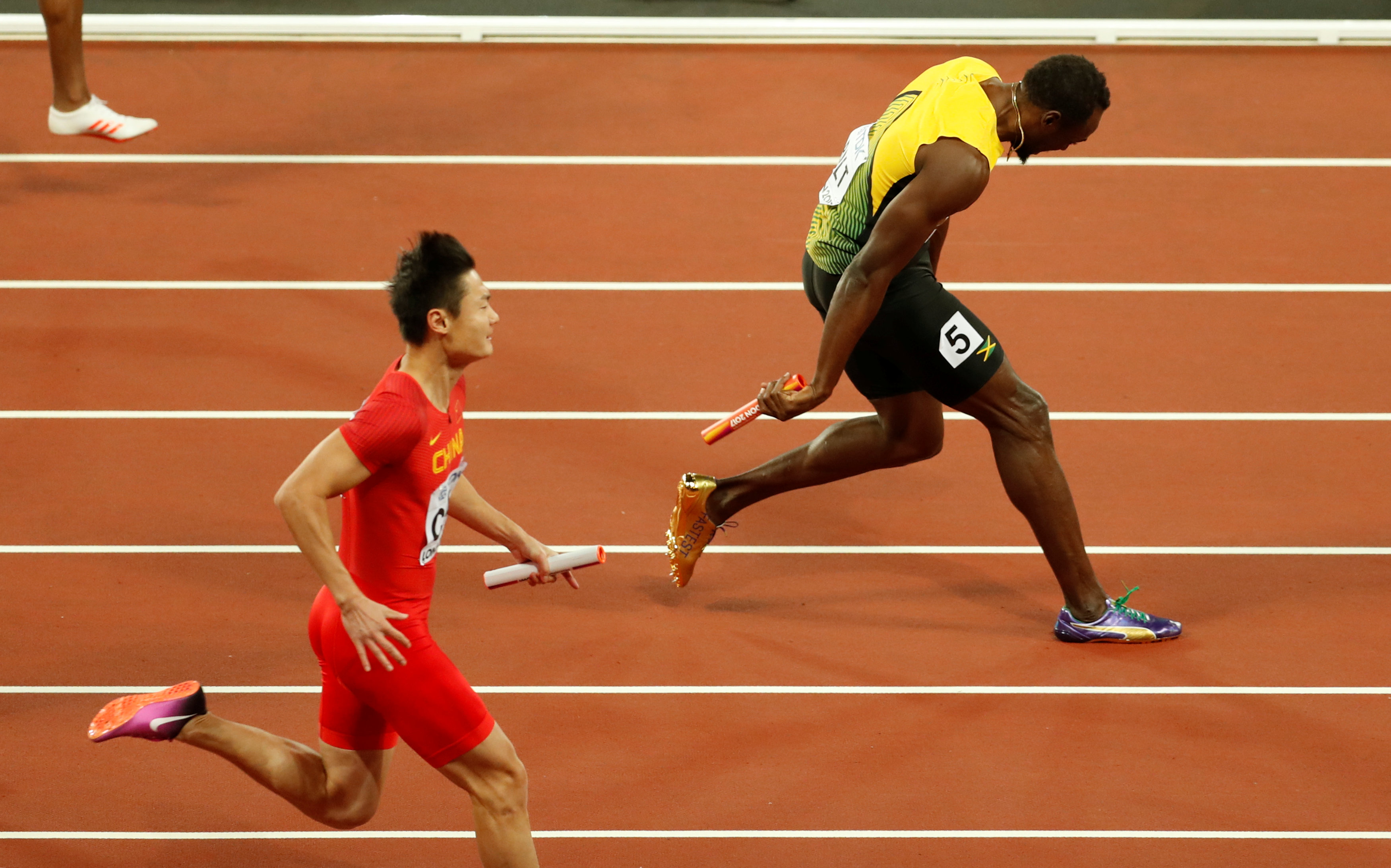 Bolt giảm tốc sau khi cố gắng chạy bằng những bước chân tập tễnh. Ảnh: REUTERS