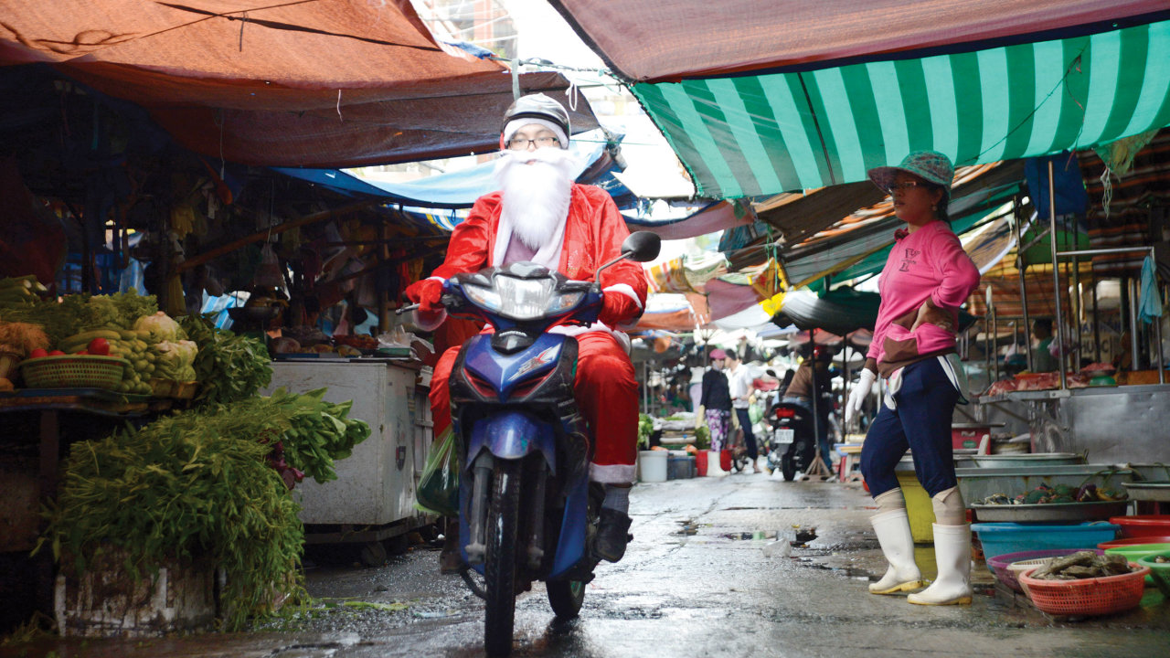 Ông già Noel len lỏi trong đường chợ để tìm đến một địa chỉ giao quà cho các bé