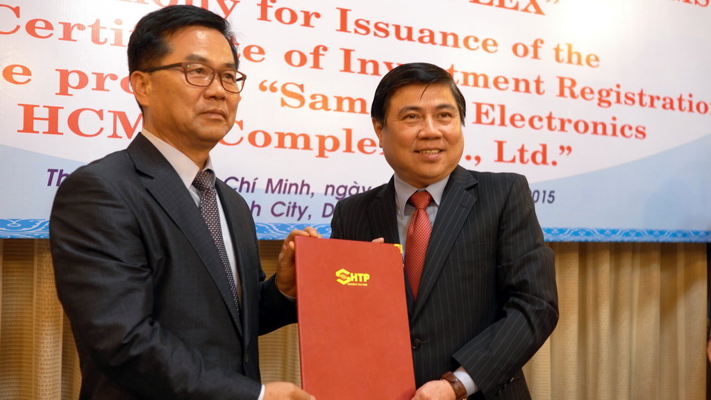 Chủ tịch UBND TP Nguyễn Thành Phong (phải) trao giấy chứng nhận đăng ký đầu tư điều chỉnh cho ông Lee Sang-Su - phó tổng giám đốc điều hành cao cấp Tập đoàn điện tử Samsung - Ảnh: T.V.N