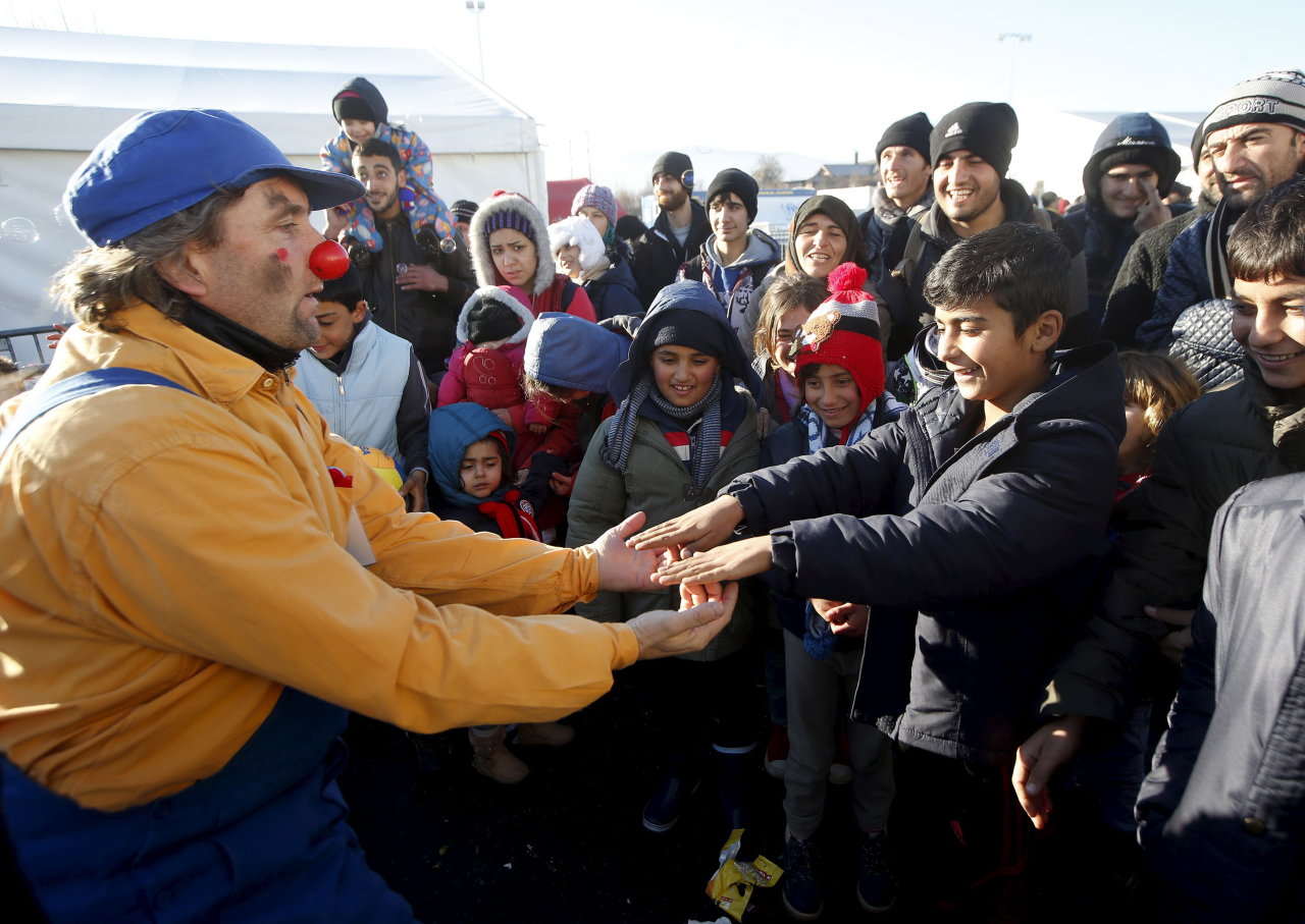 Thành viên nhóm Bác sĩ hề mũi đỏ (trái) đem lại niềm vui ngày cuối năm cho người nhập cư tại Slovenia. Cuộc khủng hoảng nhập cư đã gây nhiều hệ lụy cho châu Âu trong năm vừa qua - Ảnh: Reuters