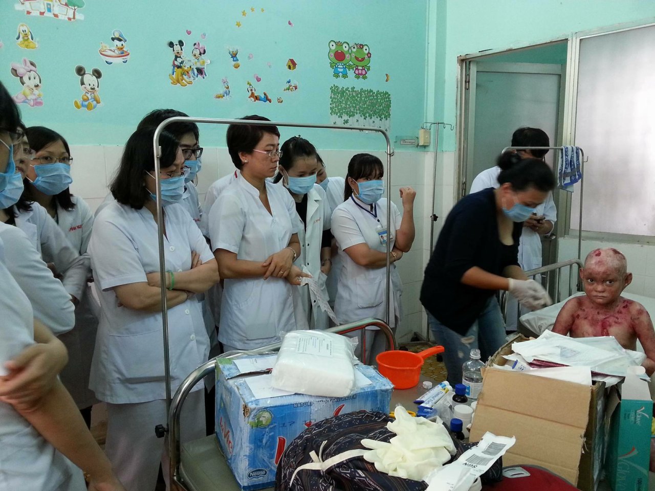 Chị Lan (áo đen) hỗ trợ các bác sĩ Bệnh viện Da liễu TP.HCM thay bông băng, chăm sóc trẻ bị EB - Ảnh: Nguyễn Thanh