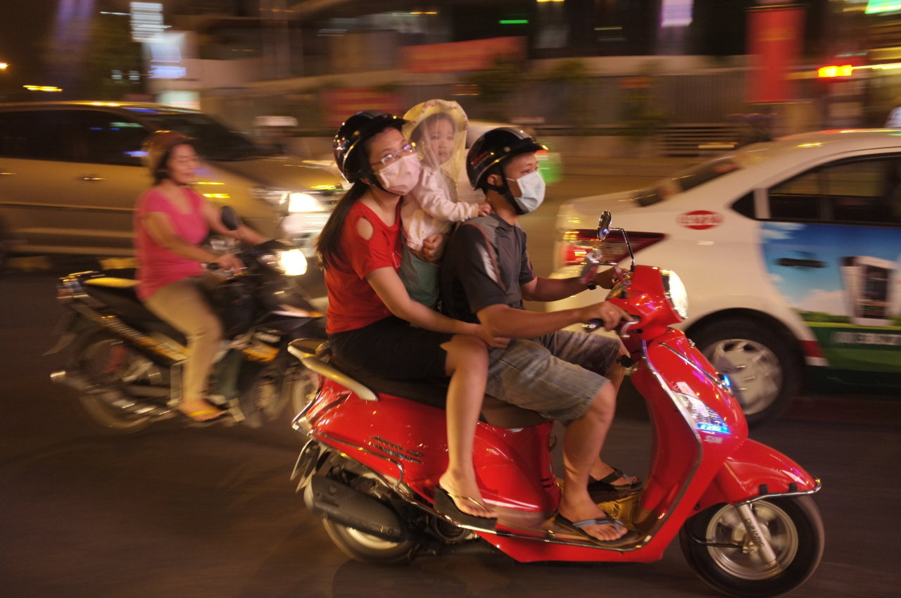 Một gia đình đưa con nhỏ đi trên đường Nguyễn Văn Trỗi, Q.Phú Nhuận, TP.HCM tối 26-1 trong trang phục mùa hè, cháu bé chỉ choàng nhẹ một khăn voan mỏng che mặt - Ảnh: Hoài Linh