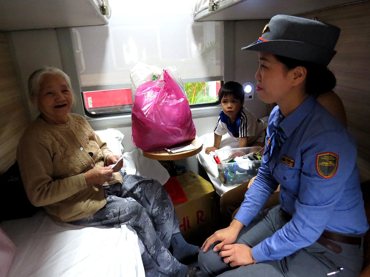 Nhân viên Nguyễn Thị Thùy Trang phát khăn lạnh cho một bà cụ lên tàu ở ga Nha Trang đi Hà Nội ngày 26-1 - Ảnh: Duy Thanh