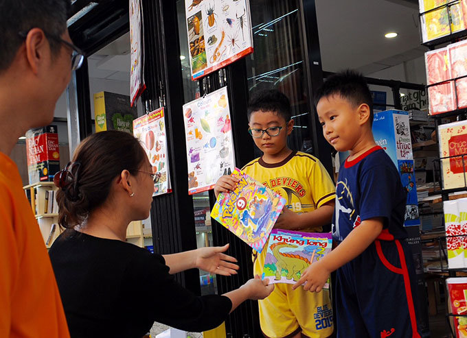 Chị Thanh Hà (quận Bình Thạnh, TP.HCM) hướng dẫn các con chọn sách, truyện tại đường sách Nguyễn Văn Bình, TP.HCM - Ảnh: Tự Trung