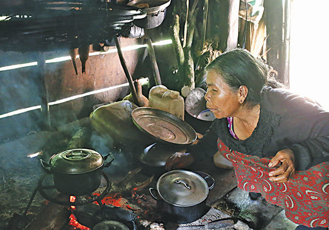Bà Cil Pan Ka Nhiên nấu ăn bằng nồi do các kiểm lâm viên tặng sau những lần ghé buôn - Ảnh: Hoàng Điệp