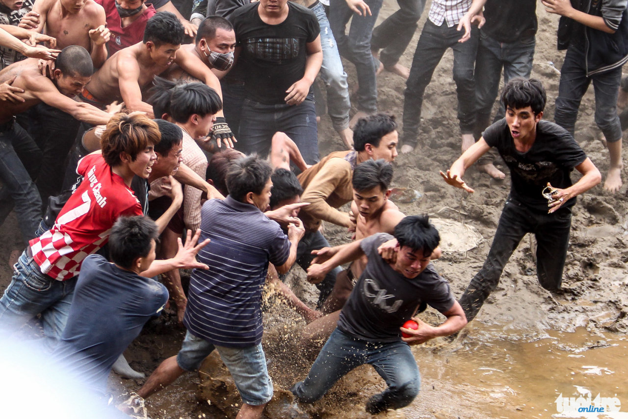 Một thanh niên cầm được quả phết cố gắng thoát khỏi đám đông và rơi vào vũng nước - Ảnh: Nguyễn Khánh
