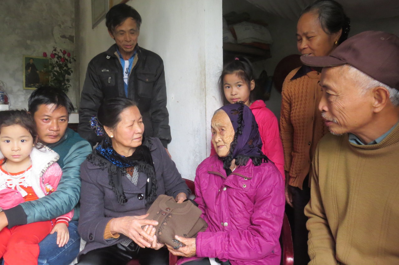 Bà Đào Thị Vui (trái) tặng áo len cho chị gái của chồng trong ngày gặp mặt năm 2016 - Ảnh: V.Toàn