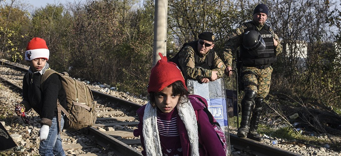 Trẻ em nhập cư đi qua chốt gác ở biên giới Macedonia - Hi Lạp - Ảnh: AFP