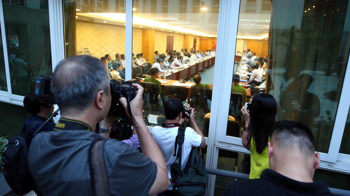 Các phóng viên tác nghiệp qua cửa kính của phòng họp - Ảnh: Nguyễn Khánh