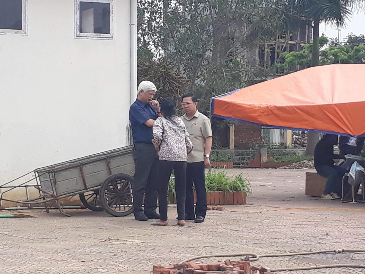 Đại biểu Quốc hội Dương Trung Quốc và Lưu Bình Nhưỡng trò chuyện với người dân trong khi chờ bàn giao người bị giữ- Ảnh: DƯƠNG LIỄU
