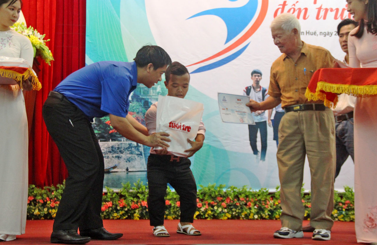 Anh Trần Gia Công (trái), phó bí thư Tỉnh đoàn Thừa Thiên - Huế cùng đại diện Hội khuyến học Thừa Thiên - Huế trao học bổng cho một tân sinh viên khuyết tật - Ảnh: MINH AN