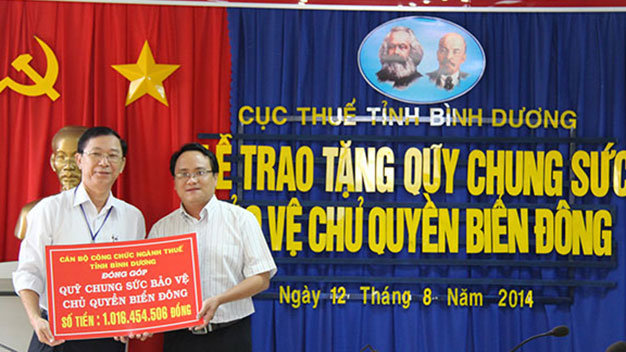 Ông Nguyễn Hoàng Nguyên, ủy viên Ban biên tập báo Tuổi Trẻ tiếp nhận ủng hộ từ ông Võ Thanh Bình-phó cục trưởng Cục thuế Bình Dương (trái) - Ảnh: Bá Sơn