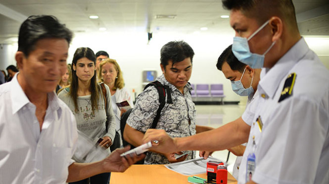 Kiểm dịch viên y tế làm nhiệm vụ đóng dấu vào tờ khai sức khỏe của hành khách trên chuyến bay từ vùng nghi có dịch đến sân bay Tân Sơn Nhất, TP.HCM (ảnh chụp tối 9-8) - Ảnh: T.T.D.