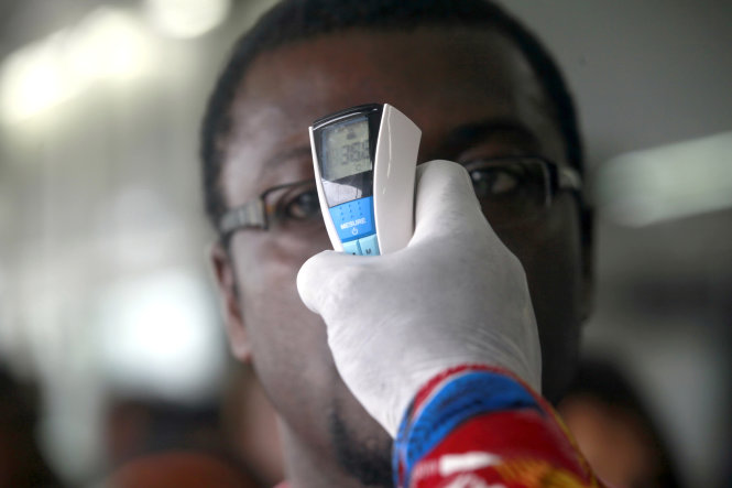 Nhân viên y tế tại sân bay Abidjan ở Bờ Biển Ngà đo thân nhiệt hành khách - Ảnh: Reuters