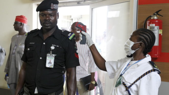 Nhân viên hải quan ở sân bay Abuja, thủ đô Nigeria, đo thân nhiệt hành khách - Ảnh: Reuters