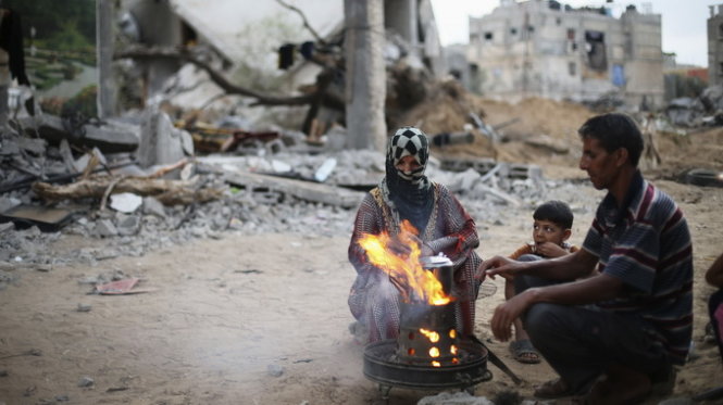 Người dân ở Palestine nấu trà trong cảnh hoang tàn trong thời gian ngừng bắn. - Ảnh: Reuters
