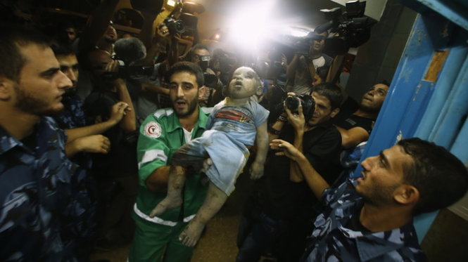 Một nhân viên y tế Gaza bế thi thể bé gái 2 tuổi bị bom đạn Israel sát hại - Ảnh: Reuters
