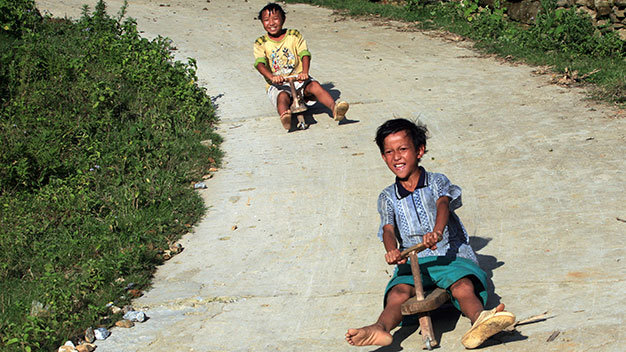  Lào Cai: Hai em Sùng A Chung và Chàng A Ký 13 tuổi, dân tộc Mông, ở bản Hòa Sú Pản 1, xã Xứ Pán, Sa Pa (Lào Cai) thả dốc “chiếc xe máy” bằng gỗ - Ảnh: Lê Bích