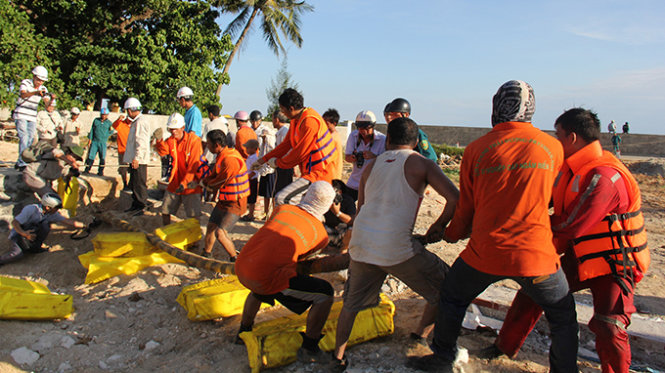Công nhân đang nổ lực kéo những met cáp cuối cùng vào trạm tiếp bờ Lý Sơn - Ảnh: Trần Mai