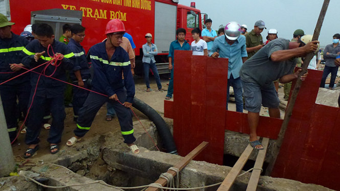 Lực lượng cứu hộ tạm ngưng bơm nước, rút ván lên bờ khi trời chuyển mưa chiều 8-9 - Ảnh: Đức Trong