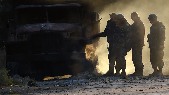 Binh sĩ Ukraine ở Mariupol kiểm tra một chiếc xe quân sự bị bắn cháy - Ảnh: AFP