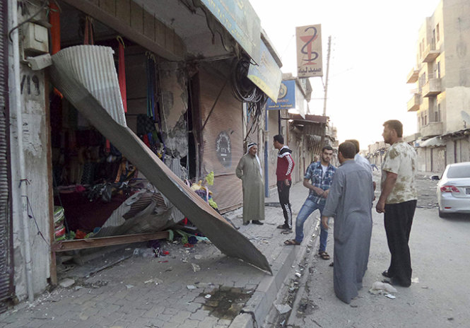 Người dân ở Raqqa trước một cửa hàng bị phá hủy hôm 23-9 - Ảnh: Reuters