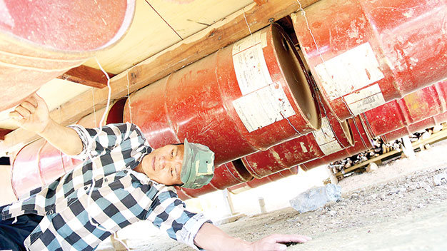 Anh Cao Sỹ Huy buộc chặt các thùng phuy dưới gầm nhà bè