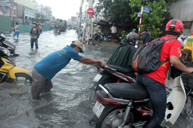 Một người dân đẩy xe giúp người đi đường - Ảnh Đức Phú