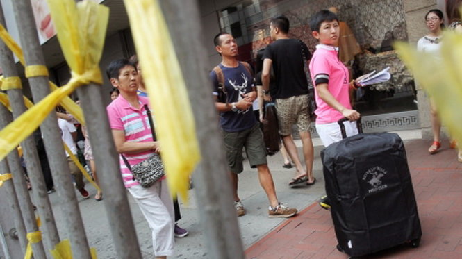 Một khách du lịch Trung Quốc đi ngang một khu biểu tình ở Causeway Bay - Ảnh: imaginechina.com