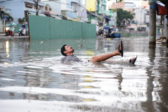 Một người dân ngã khi qua đường Tân Hóa ngập nước chiều 1-10 - Ảnh: Hữu Khoa