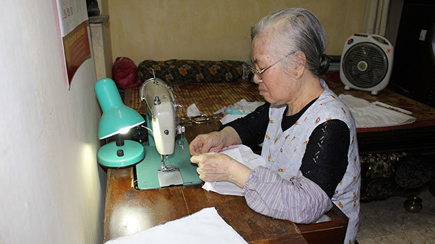 Bà Phúc bị suy tim vẫn miệt mài may quần áo cho trẻ em nghèo - Ảnh: Nguyễn Hường