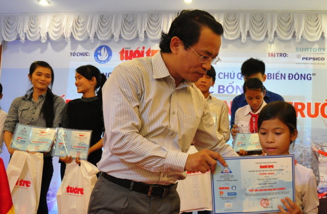 Đại diện của Công ty TNHH nước giải khát Suntory Fepsico Việt Nam tại miền trung trao học bổng “Tiếp sức con ngư dân đến trường” cho học sinh - Ảnh: Tấn Vũ 