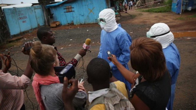 Các phóng viên địa phương và nước ngoài phỏng vấn một bác sĩ bên ngoài một trung tâm chữa trị Ebola ở Monrovia, Liberia - Ảnh: SFGate