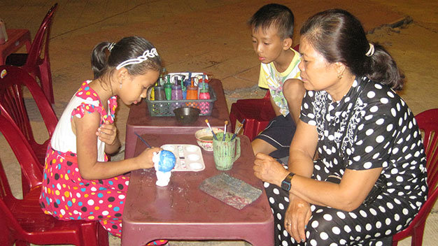 Bà giáo Hiệp bên mấy đứa trẻ tô tượng - Ảnh: Sương Trang
